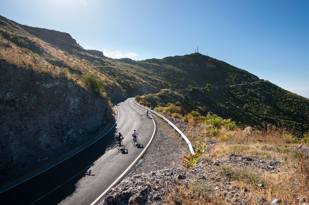 Ciclisti su una strada montuosa a Tenerife sotto un cielo limpido.