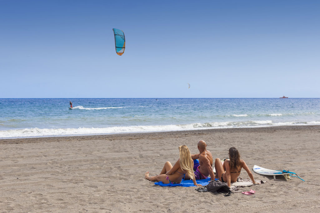 Persone che osservano un kitesurfista sulla spiaggia di El Médano, Tenerife.
