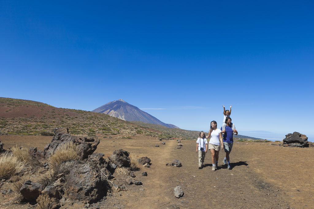 Famiglia che cammina attraverso il paesaggio vulcanico del Monte Teide, Tenerife.