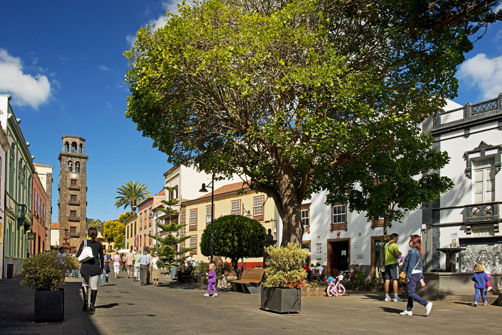 Persone che camminano nella piazza con il torre della chiesa a La Laguna, Tenerife.