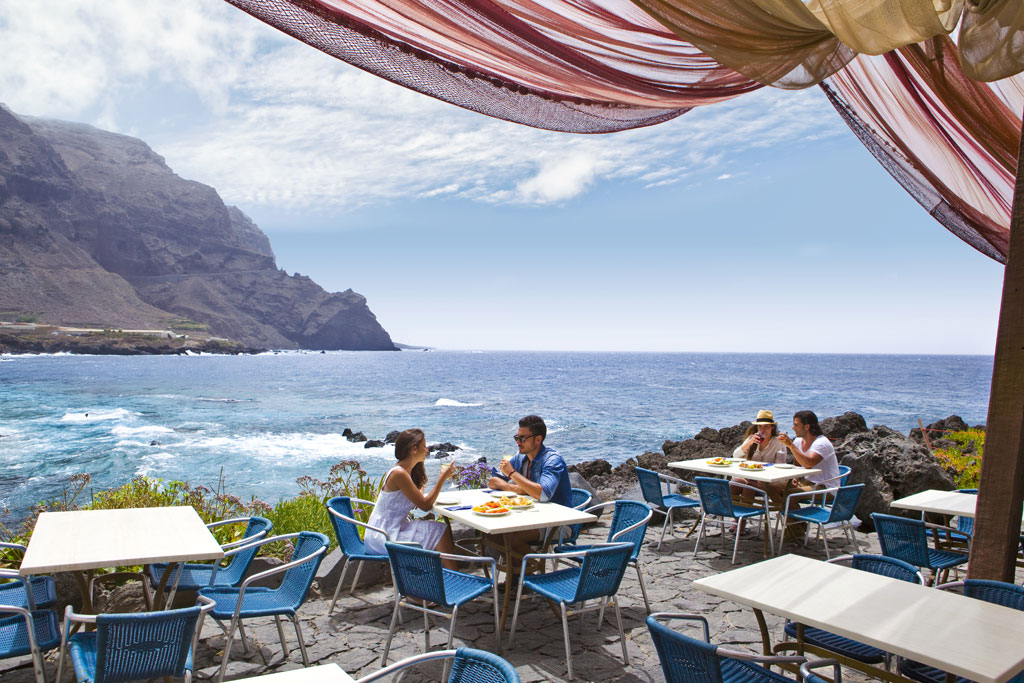 Terrazza fronte mare a Tenerife con persone che mangiano sotto un cielo limpido.
