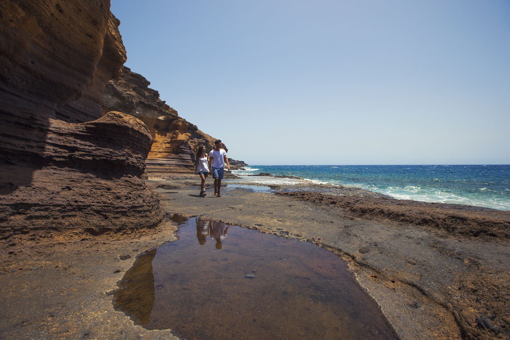 Persone che camminano sulla costa rocciosa di Tenerife al mare.
