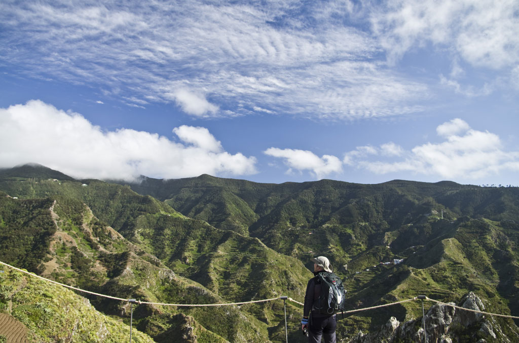 Persona che osserva le verdi montagne di Anaga a Tenerife sotto un cielo parzialmente nuvoloso.
