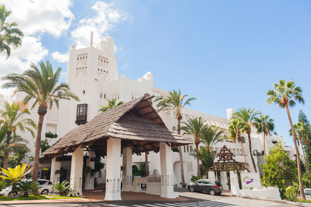 Ingresso principale di un hotel con architettura bianca e palme a Tenerife.
