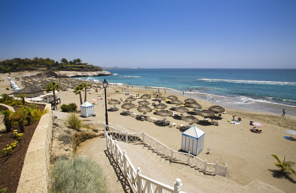 Playa del Duque a Tenerife con ombrelloni e bagnanti che si godono il sole.