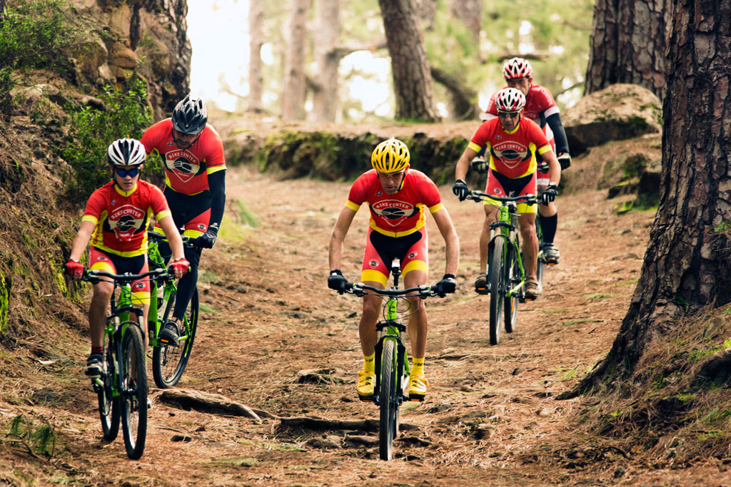 Ciclisti su un percorso forestale a Tenerife indossando uniformi rosse e nere.