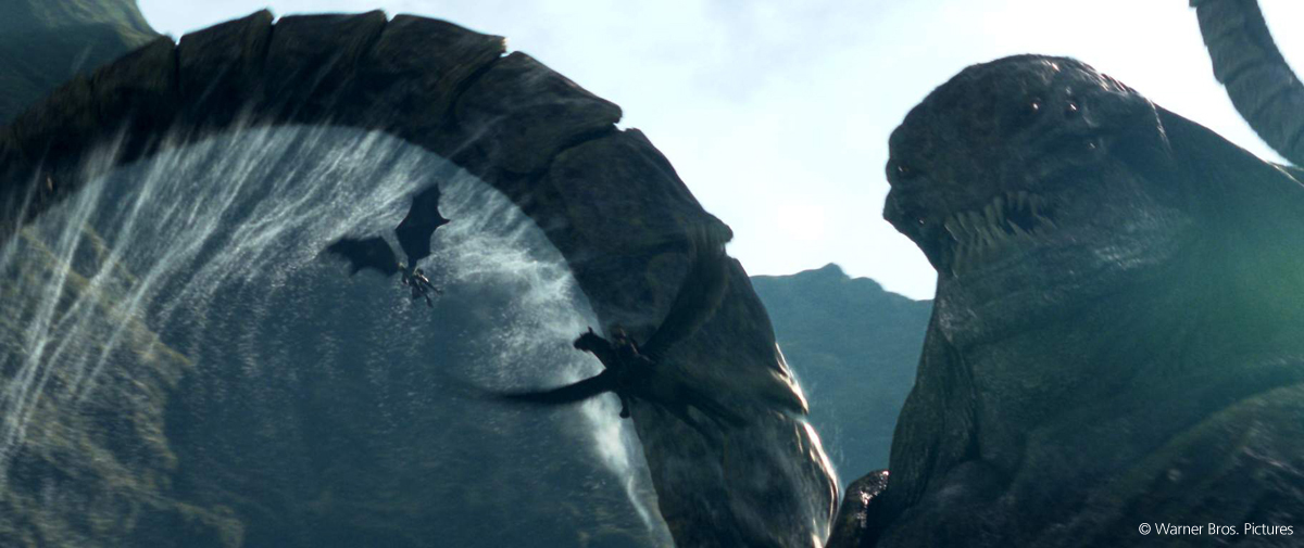 Creatura gigante a forma di mostro marino davanti a draghi che vola tra montagne e un'enorme onda.