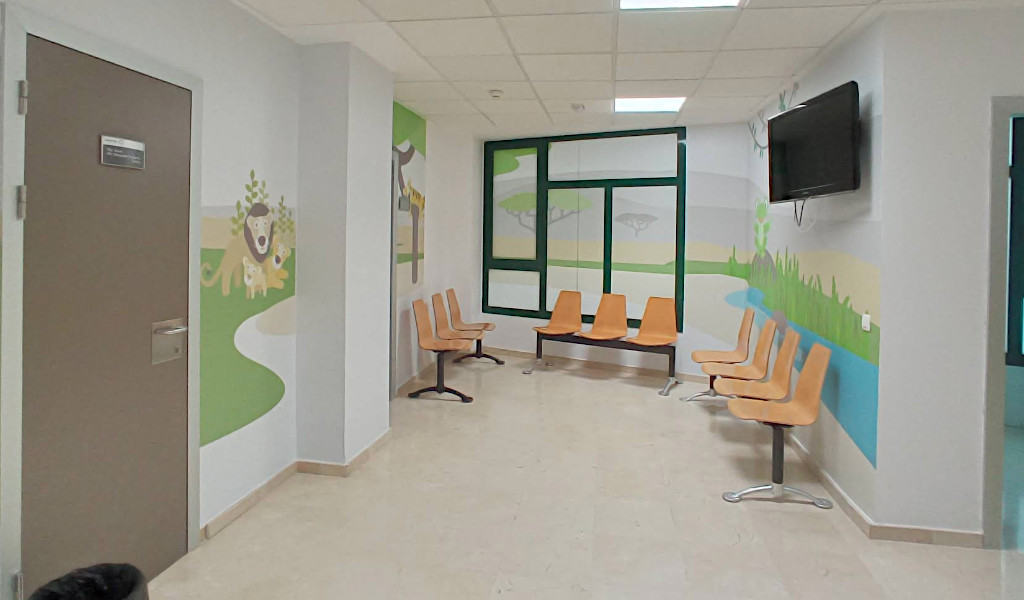 Sala d'attesa con sedie arancioni e murales colorati a Tenerife.