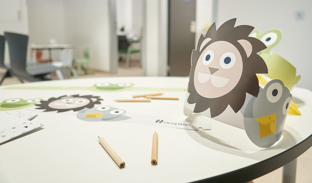 Tavolo con materiali per il lavoro per bambini in un ospedale di Tenerife, incluse ghirlande di carta con motivi di animali.