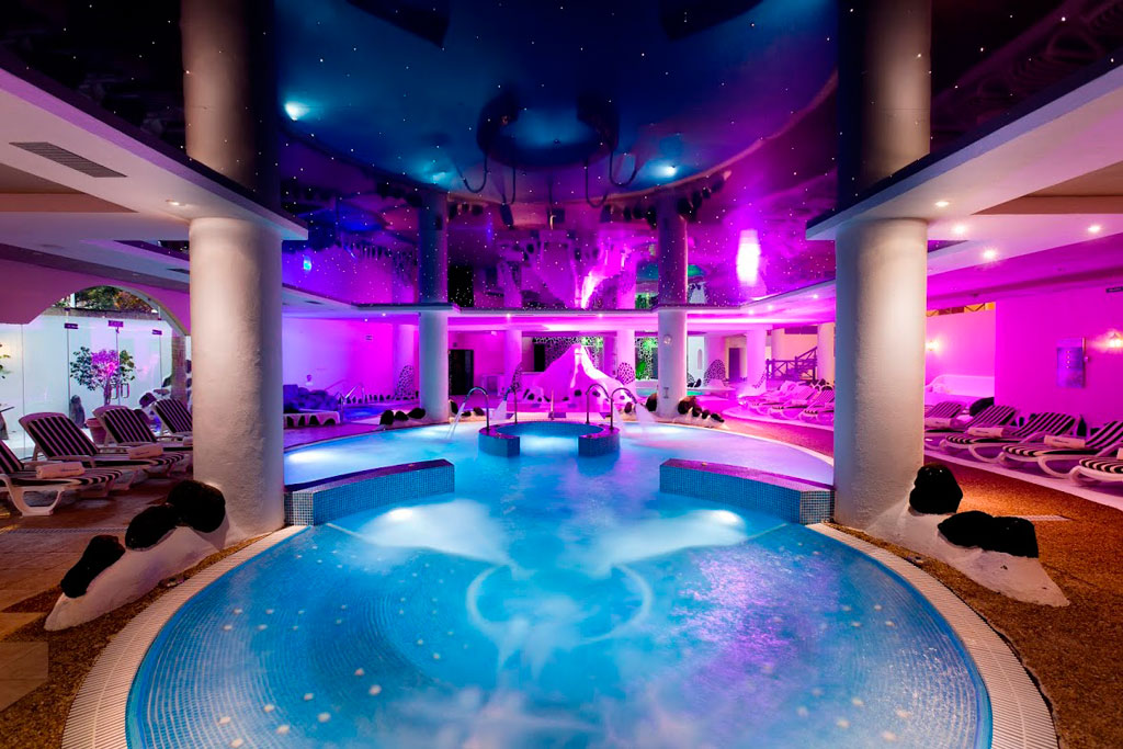 Piscina coperta illuminata nella spa di Tenerife con sdrai per il sole tutto intorno.
