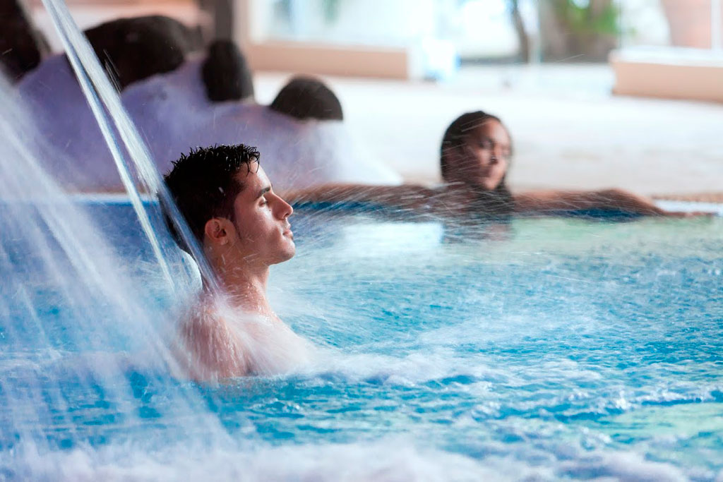 Uomo che si gode un getto d'acqua in una piscina a Tenerife.