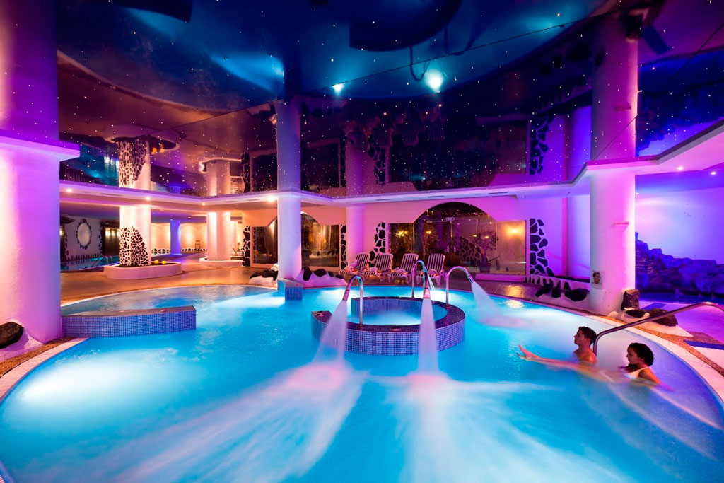 Piscina coperta illuminata in una spa a Tenerife con due persone che si rilassano.