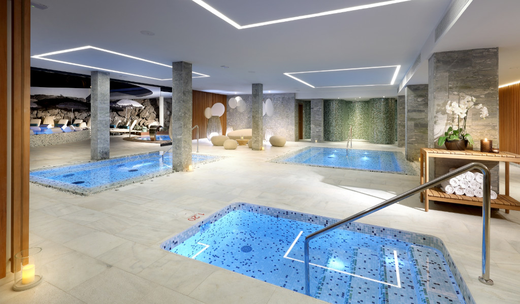 Piscina coperta con jacuzzi in una spa a Tenerife, circondata da piante e lampade.