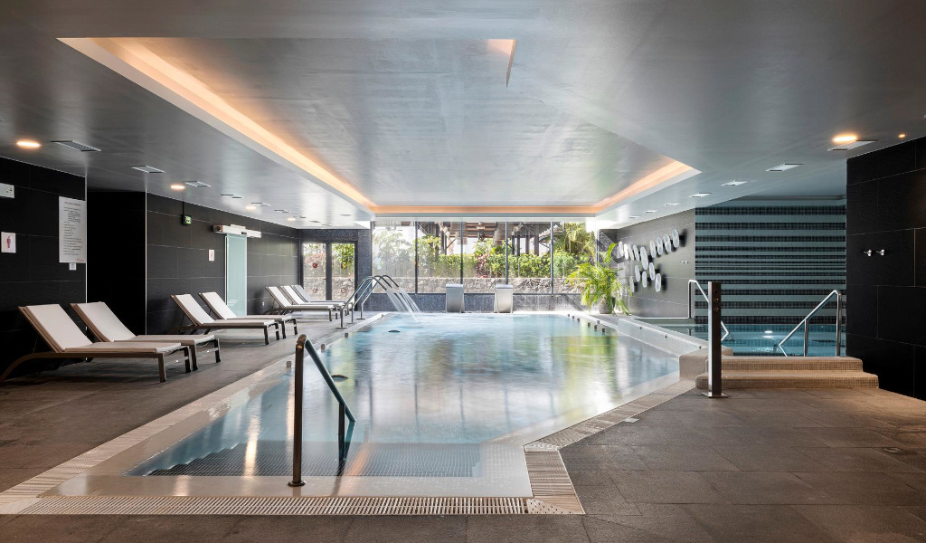 Piscina coperta a Tenerife con sdraio e piante accanto alle finestre.