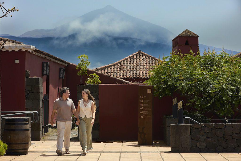 Persone che camminano vicino a case tradizionali con il Monte Teide sullo sfondo a Tenerife.