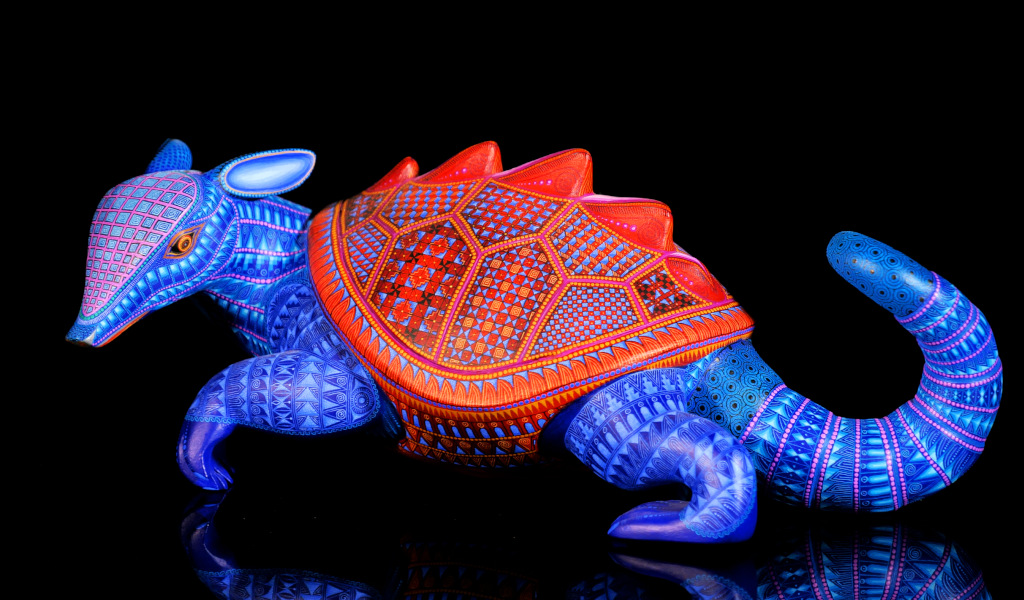 Armadillo di legno intagliato con colori vivaci e disegni geometrici.