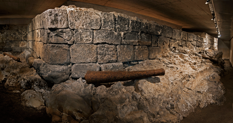 Rovine di una mura storica a Tenerife illuminate sotto un tetto in cemento.