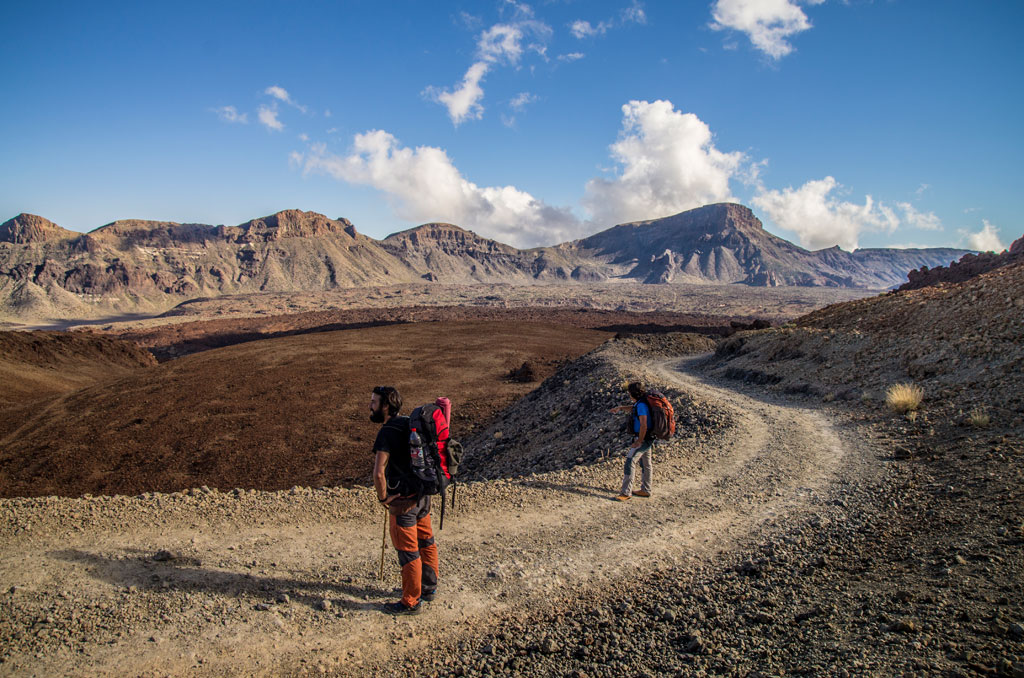 Sentiero di montagna sul Teide, Tenerife, con due persone che camminano sotto un cielo azzurro.