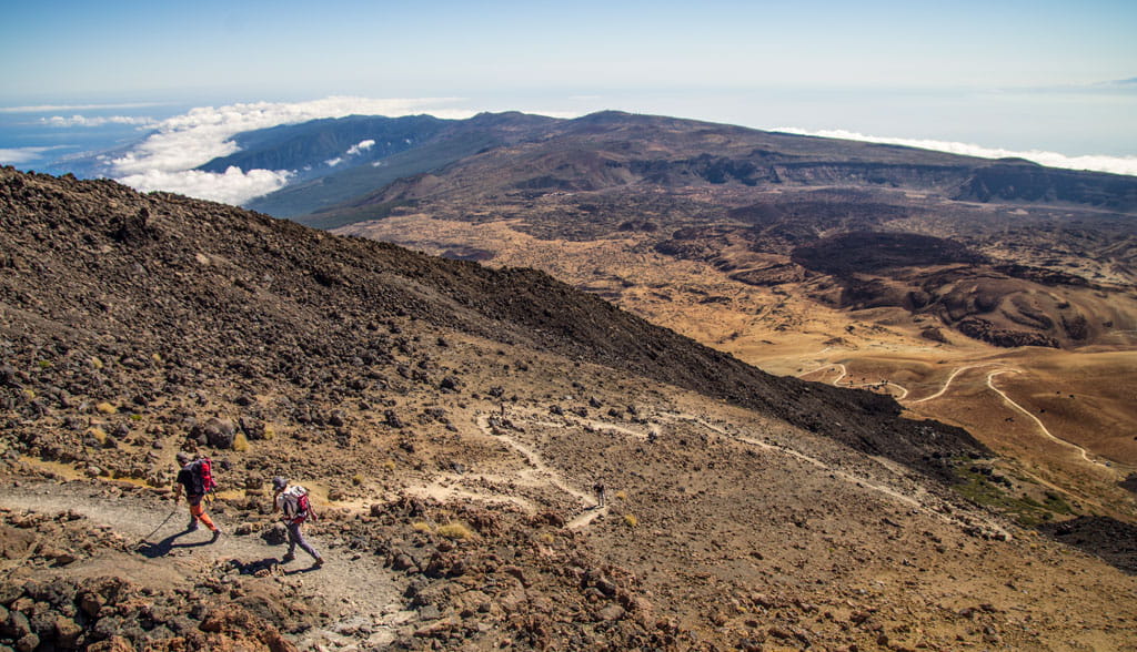 Escursionisti sul Monte Teide, Tenerife, con paesaggio vulcanico sullo sfondo.