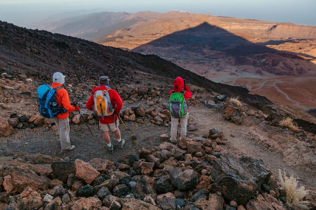 Tre escursionisti percorrono sentieri rocciosi nel Parco Nazionale del Teide, Tenerife.