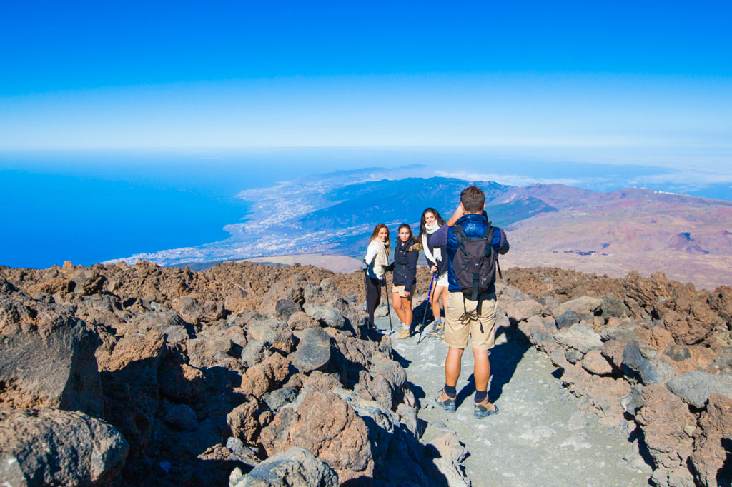 Gruppo di persone su sentiero roccioso con vista sul mare e paesaggi di Tenerife.