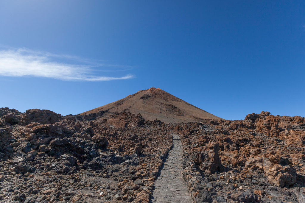 Un sentiero di ciottoli verso il Monte Teide a Tenerife sotto un cielo azzurro.