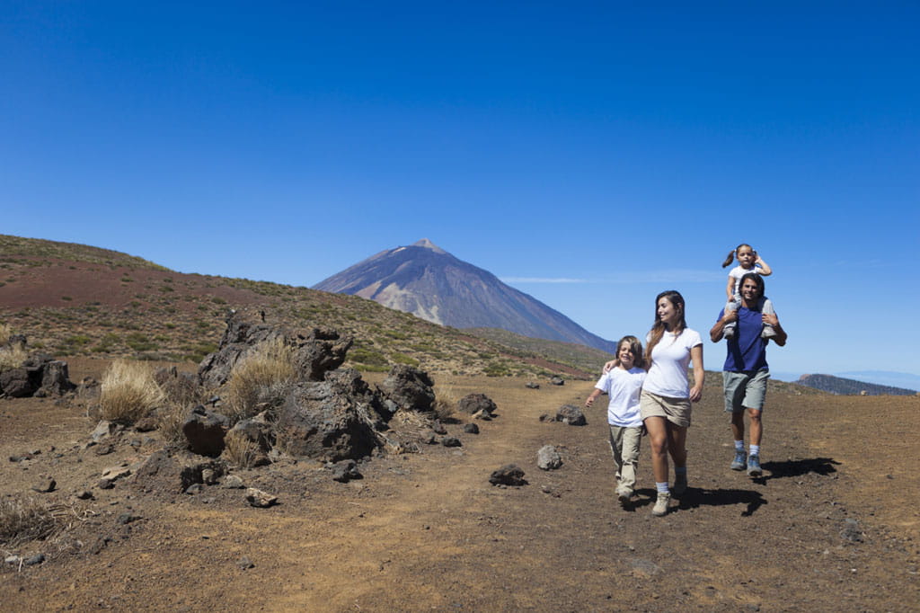 Famiglia che passeggia vicino al vulcano del Teide a Tenerife sotto un cielo limpido.