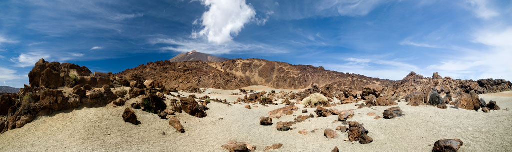 Paesaggio vulcanico del Monte Teide a Tenerife sotto un cielo azzurro con nuvole sparse.