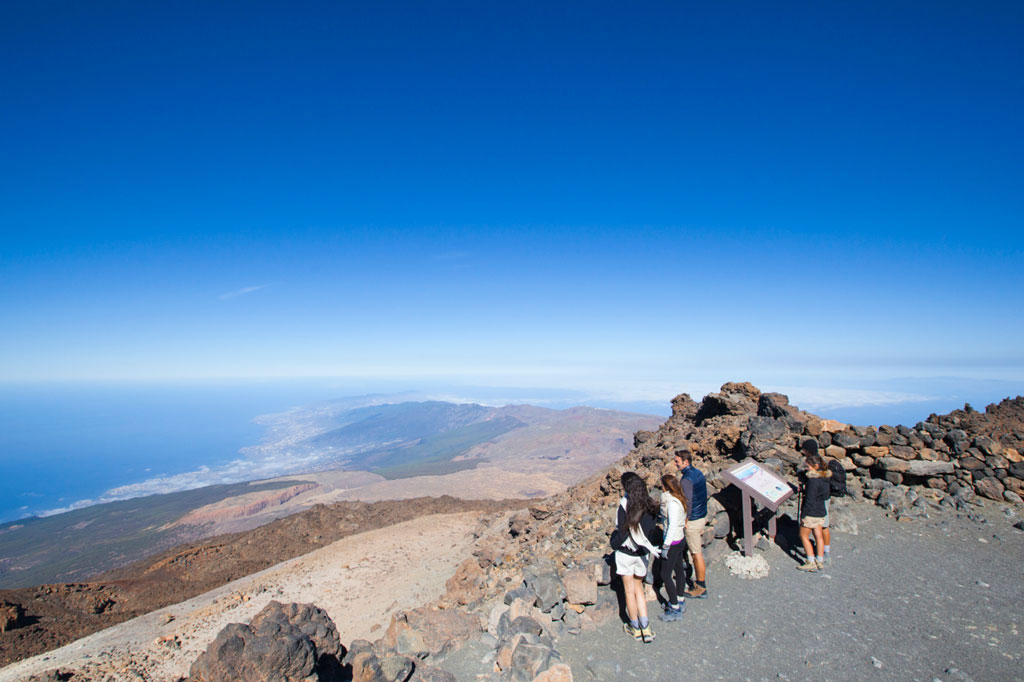 Persone che osservano il paesaggio dal Monte Teide a Tenerife, con l'oceano sullo sfondo.