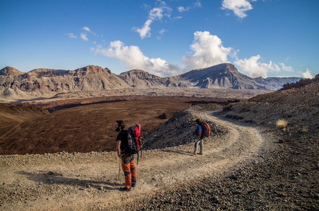 Sentiero nel Parco Nazionale del Teide, Tenerife, con montagne sullo sfondo.