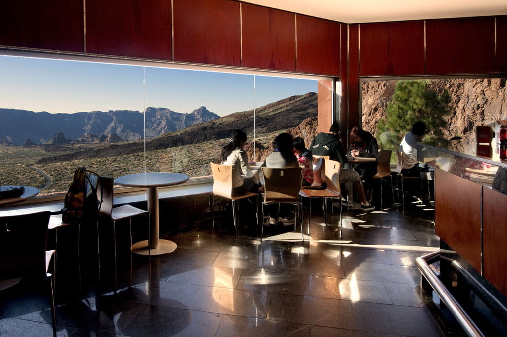 Vista del Monte Teide da un caffè a Tenerife con persone sedute vicino alla finestra.
