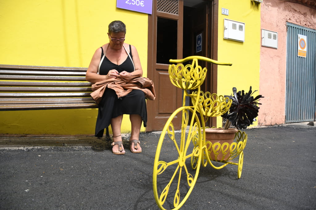 Donna seduta su una panchina accanto a una bicicletta decorativa a Tenerife.