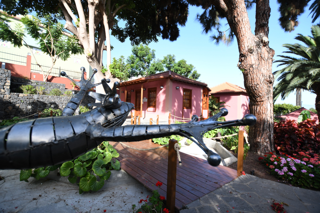 Scultura di lucertola metallica davanti a una casa rosa a Puerto de la Cruz, Tenerife.