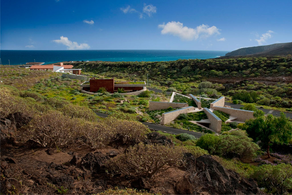 Centro visitatori a Punta de Teno, Tenerife, circondato da verde e mare sullo sfondo.