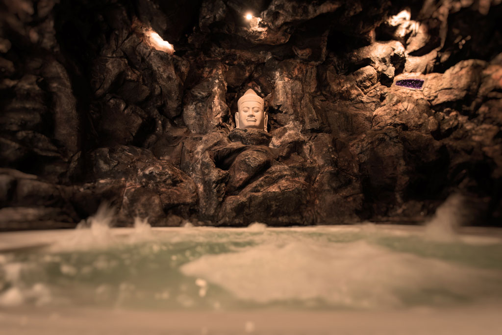 Busto di Buddha in una grotta rocciosa con acqua alla base a Tenerife.