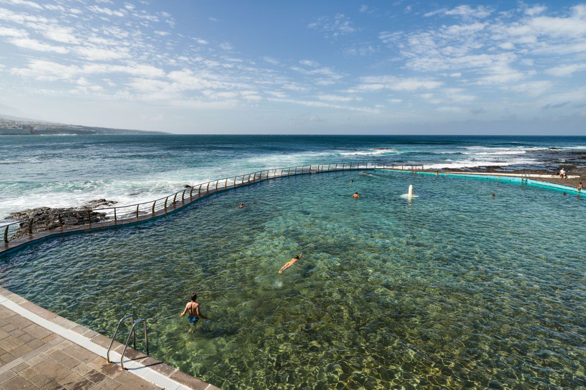 Piscina naturale a Tenerife sul mare con diverse persone che nuotano.