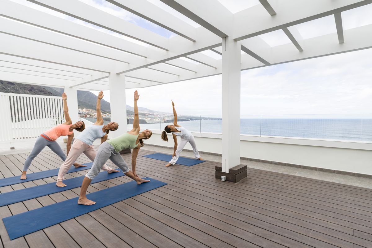 Pratica di gruppo di yoga all'aperto con vista sul mare a Tenerife.