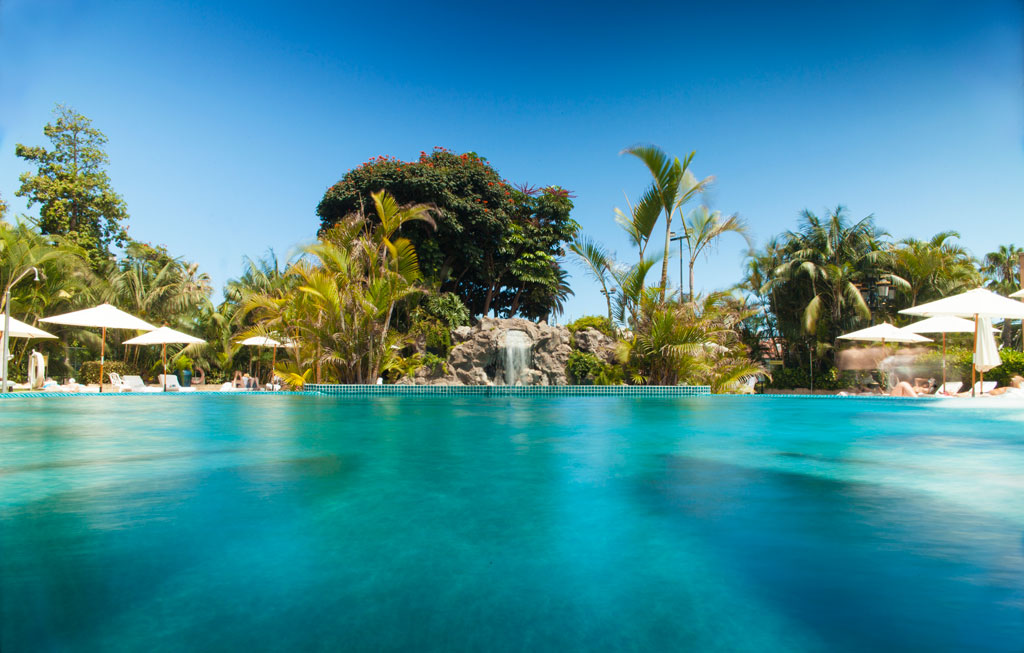 Piscina con ombrelli e vegetazione tropicale in un hotel a Tenerife.